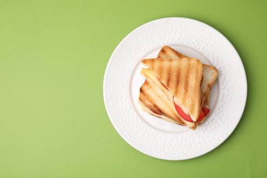 Photo of Pieces of toasted bread with melted cheese and tomato on green table, top view. Space for text