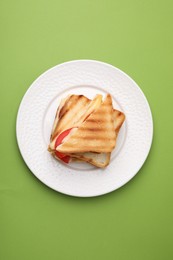 Pieces of toasted bread with melted cheese and tomato on green table, top view