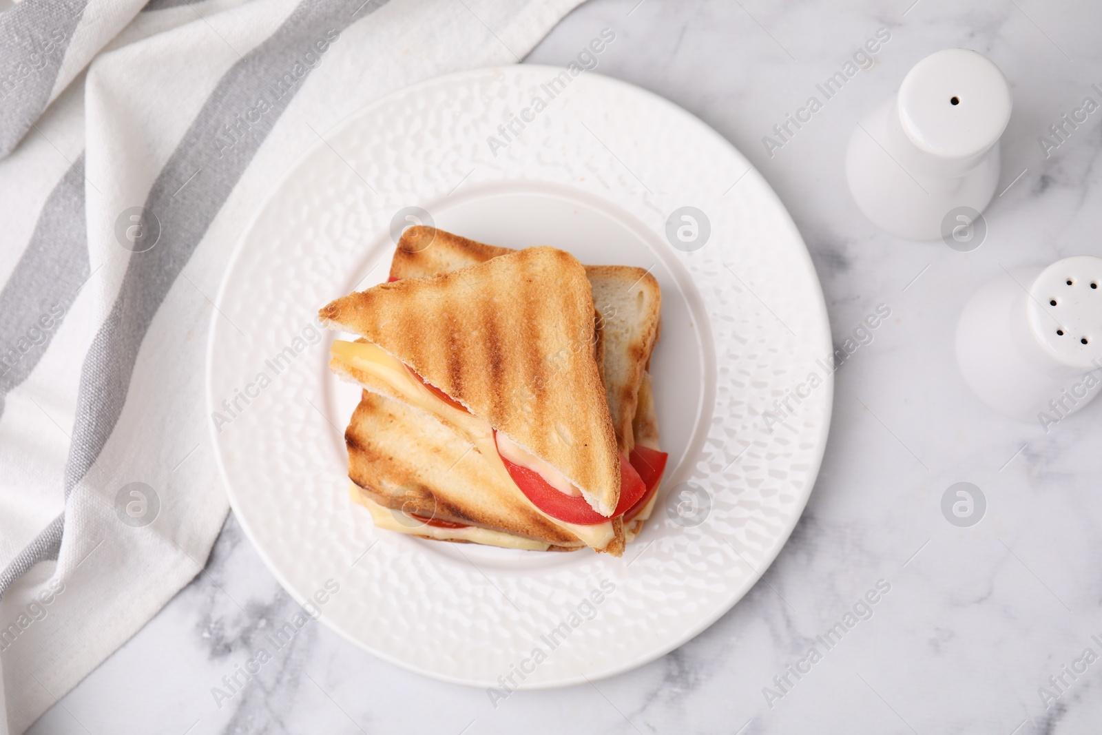 Photo of Pieces of toasted bread with melted cheese, tomato and spices on light marble table, flat lay