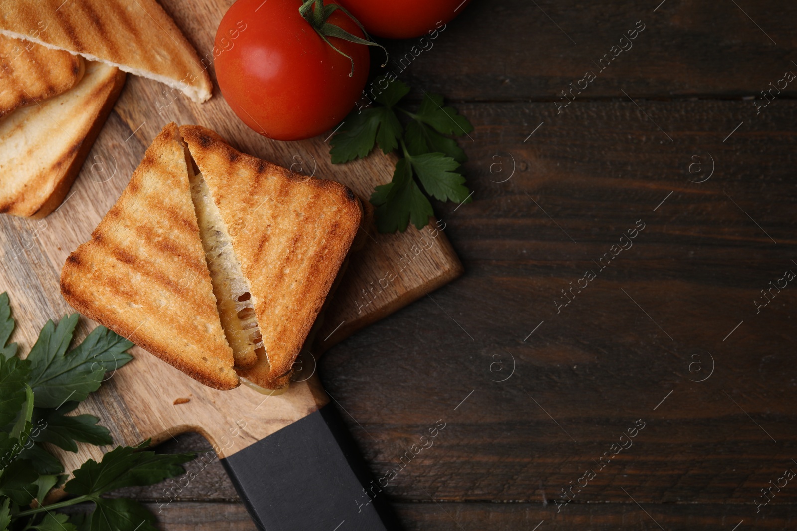 Photo of Pieces of toasted bread with melted cheese, tomatoes and parsley on wooden table, flat lay. Space for text