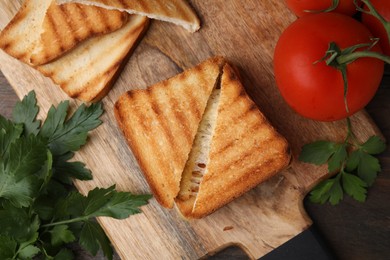 Pieces of toasted bread with melted cheese, tomatoes and parsley on table, top view