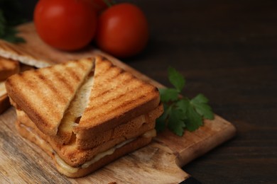 Photo of Pieces of toasted bread with melted cheese, tomatoes and parsley on wooden table, closeup. Space for text