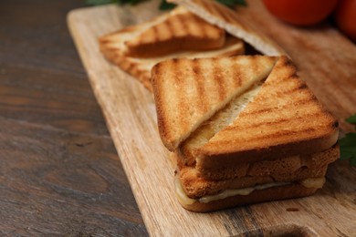 Pieces of toasted bread with melted cheese on wooden table, closeup