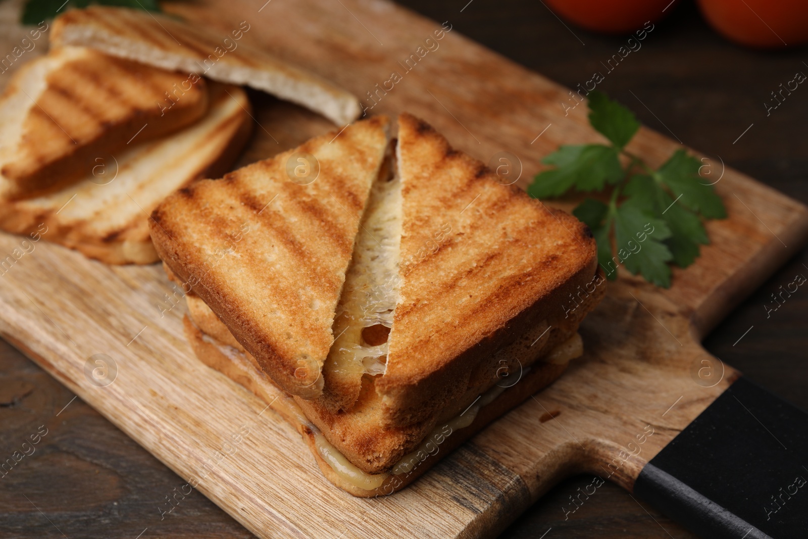 Photo of Pieces of toasted bread with melted cheese on wooden table, closeup