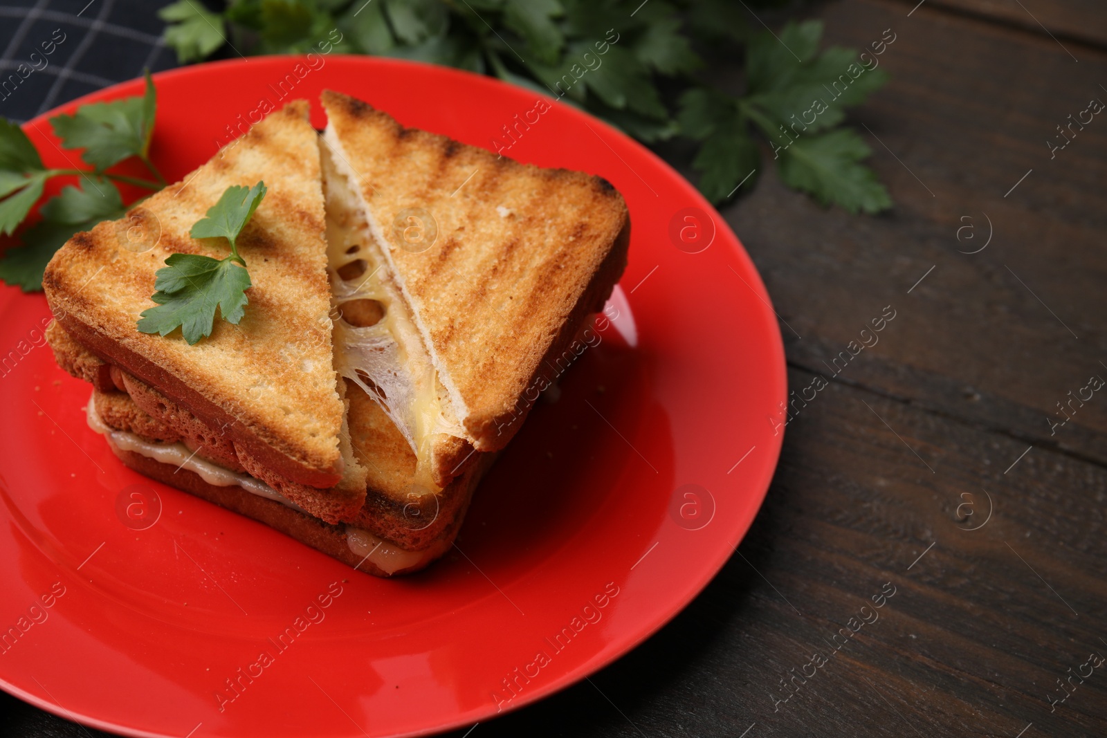 Photo of Pieces of toasted bread with melted cheese and parsley on wooden table, closeup. Space for text