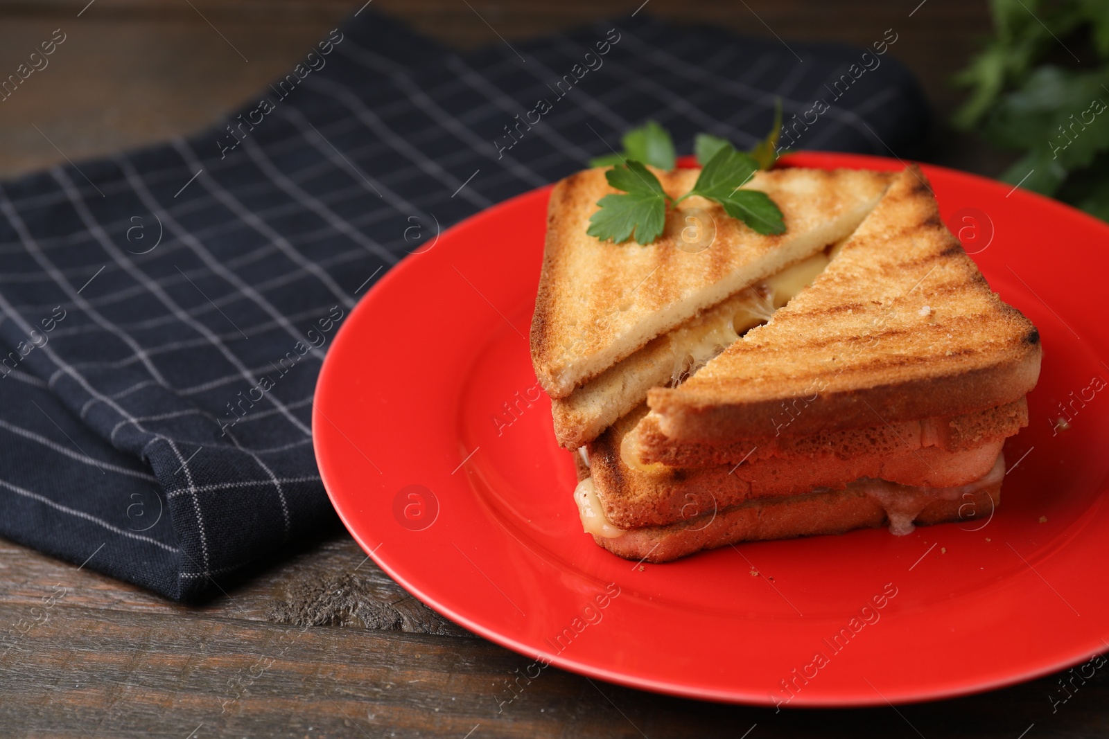 Photo of Pieces of toasted bread with melted cheese and parsley on wooden table, closeup