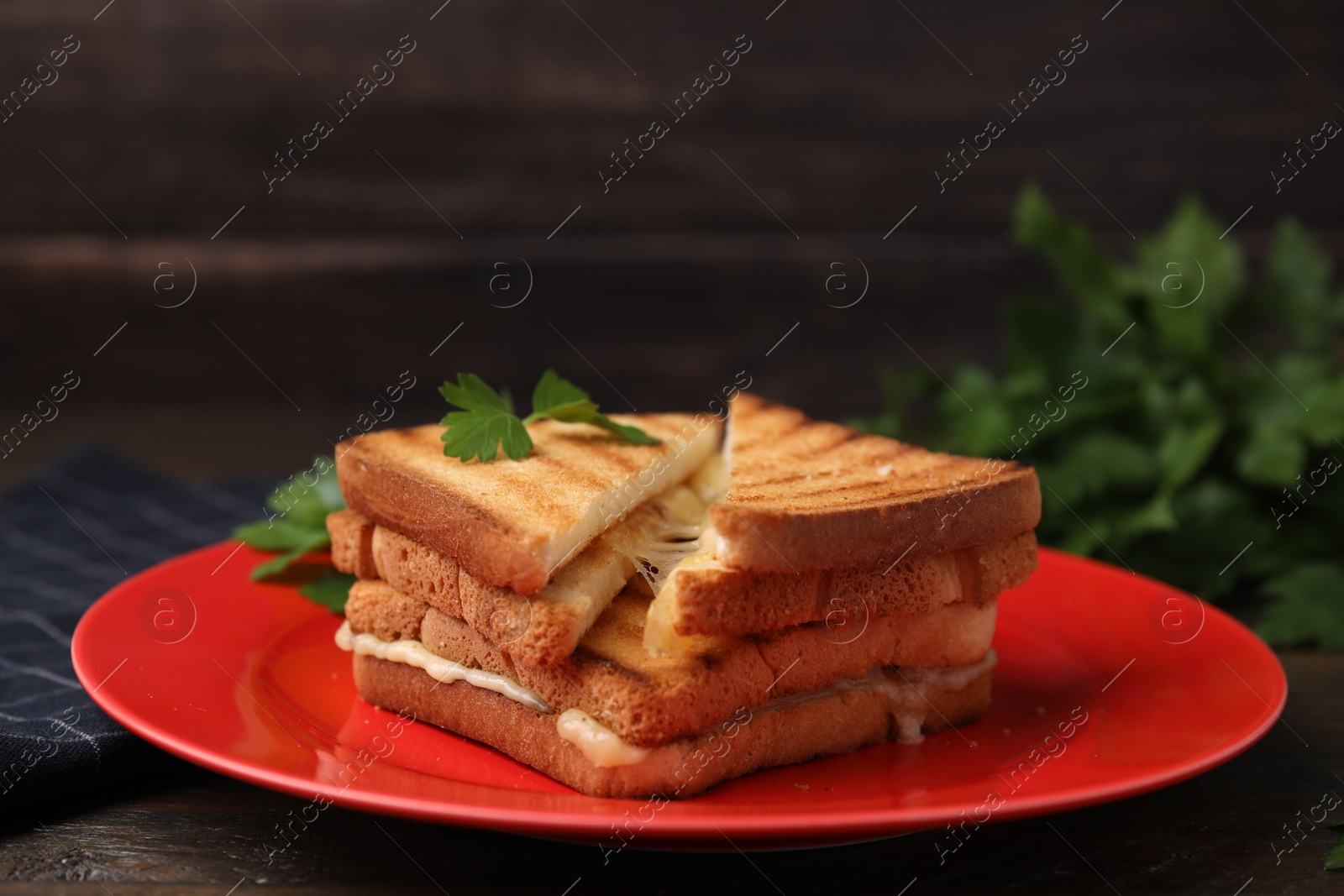 Photo of Pieces of toasted bread with melted cheese and parsley on wooden table, closeup