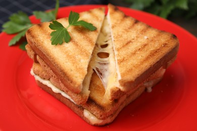 Photo of Pieces of toasted bread with melted cheese and parsley on red plate, closeup