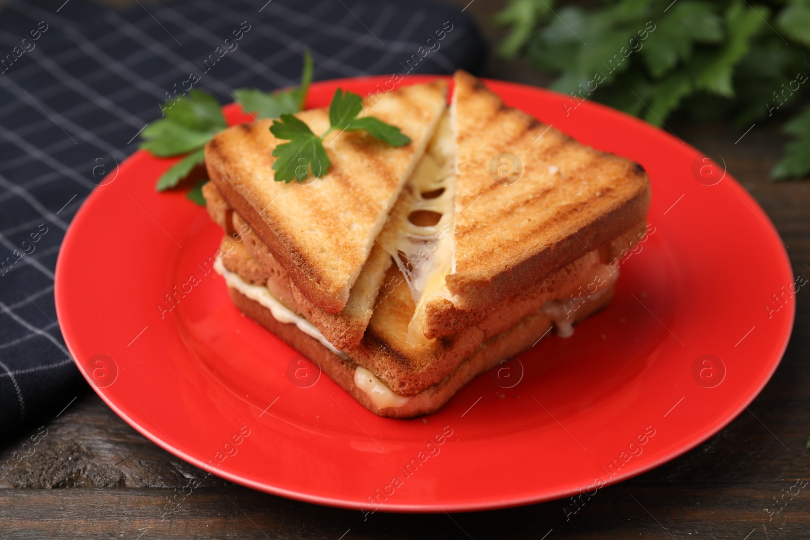 Photo of Pieces of toasted bread with melted cheese and parsley on wooden table, closeup