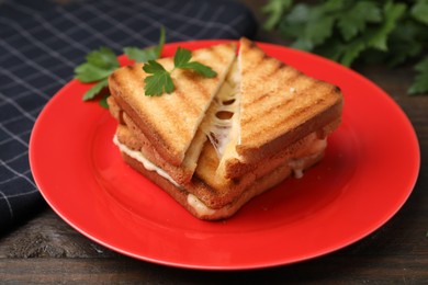 Pieces of toasted bread with melted cheese and parsley on wooden table, closeup