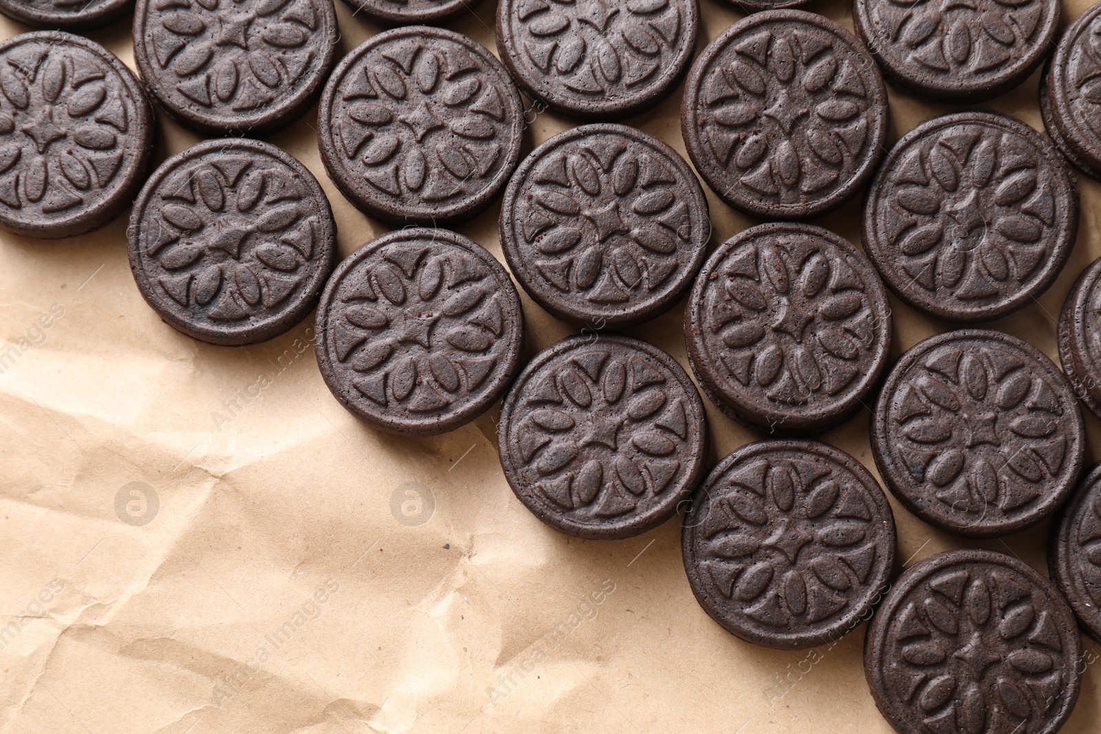 Photo of Tasty sandwich cookies on parchment paper, top view