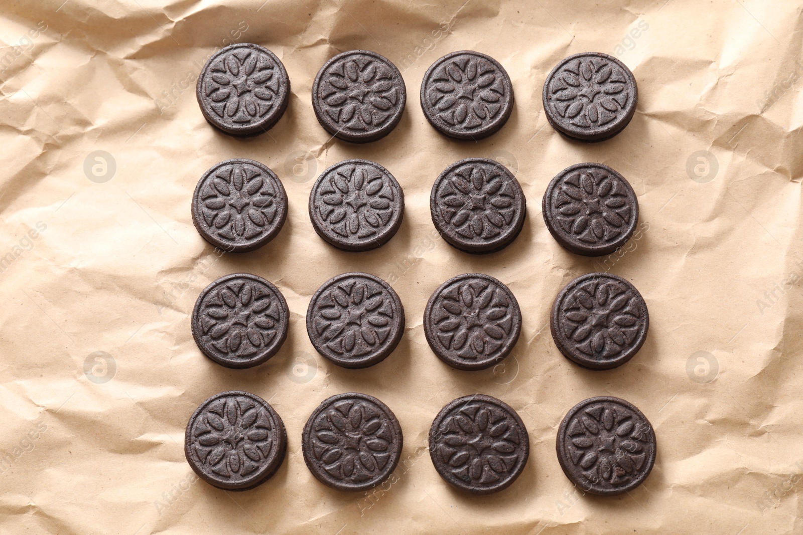 Photo of Tasty sandwich cookies on parchment paper, top view