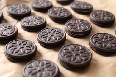 Photo of Many tasty sandwich cookies on parchment paper, closeup