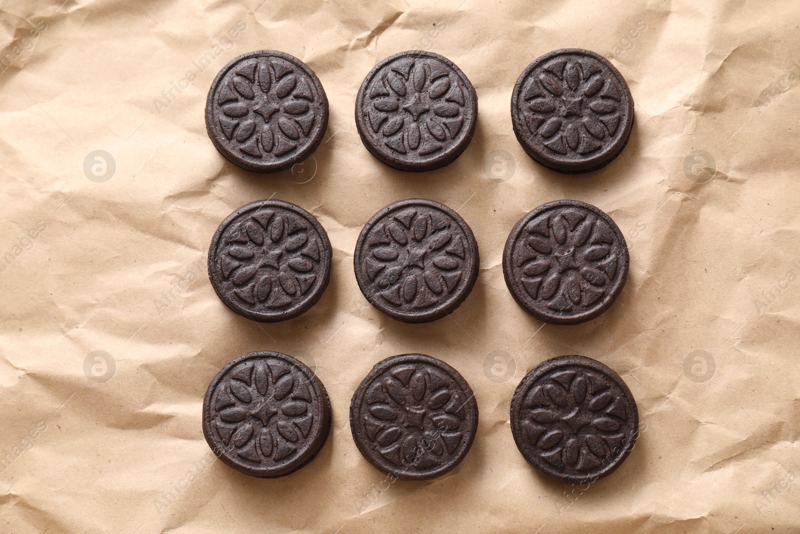 Photo of Tasty sandwich cookies on parchment paper, top view