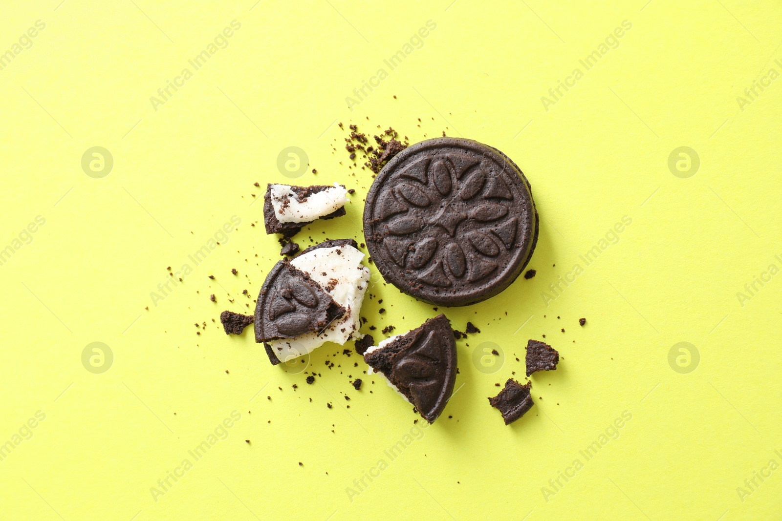 Photo of Whole and broken sandwich cookies on green background, top view