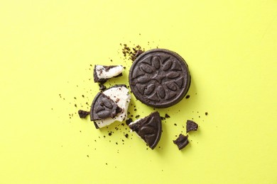 Photo of Whole and broken sandwich cookies on green background, top view