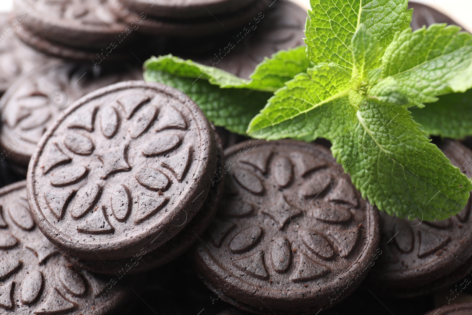 Photo of Tasty sandwich cookies and mint leaves, closeup