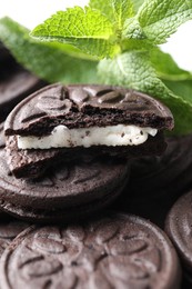 Photo of Tasty sandwich cookies and mint leaves, closeup