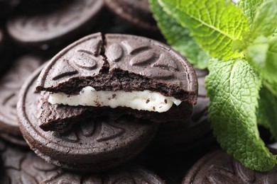 Photo of Tasty sandwich cookies and mint leaves, closeup