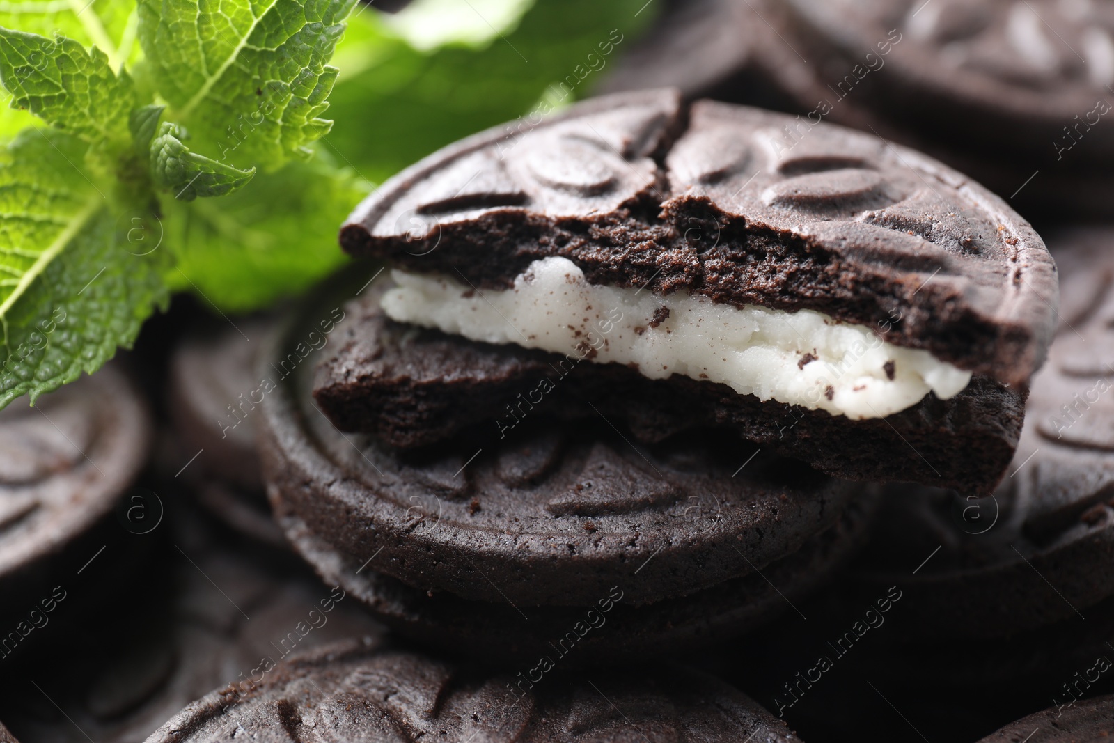 Photo of Tasty sandwich cookies and mint leaves, closeup