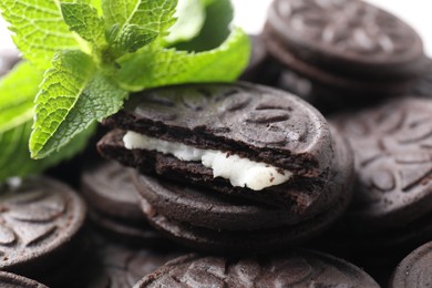 Photo of Tasty sandwich cookies and mint leaves, closeup