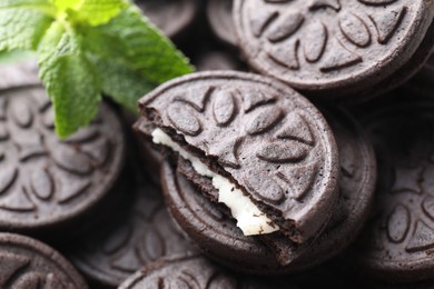 Photo of Tasty sandwich cookies and mint leaves, closeup