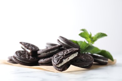 Photo of Tasty sandwich cookies and mint on white marble table