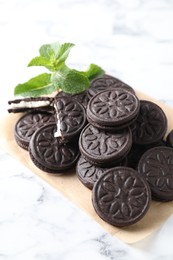 Photo of Tasty sandwich cookies and mint on white marble table