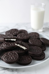 Tasty sandwich cookies and milk on white marble table