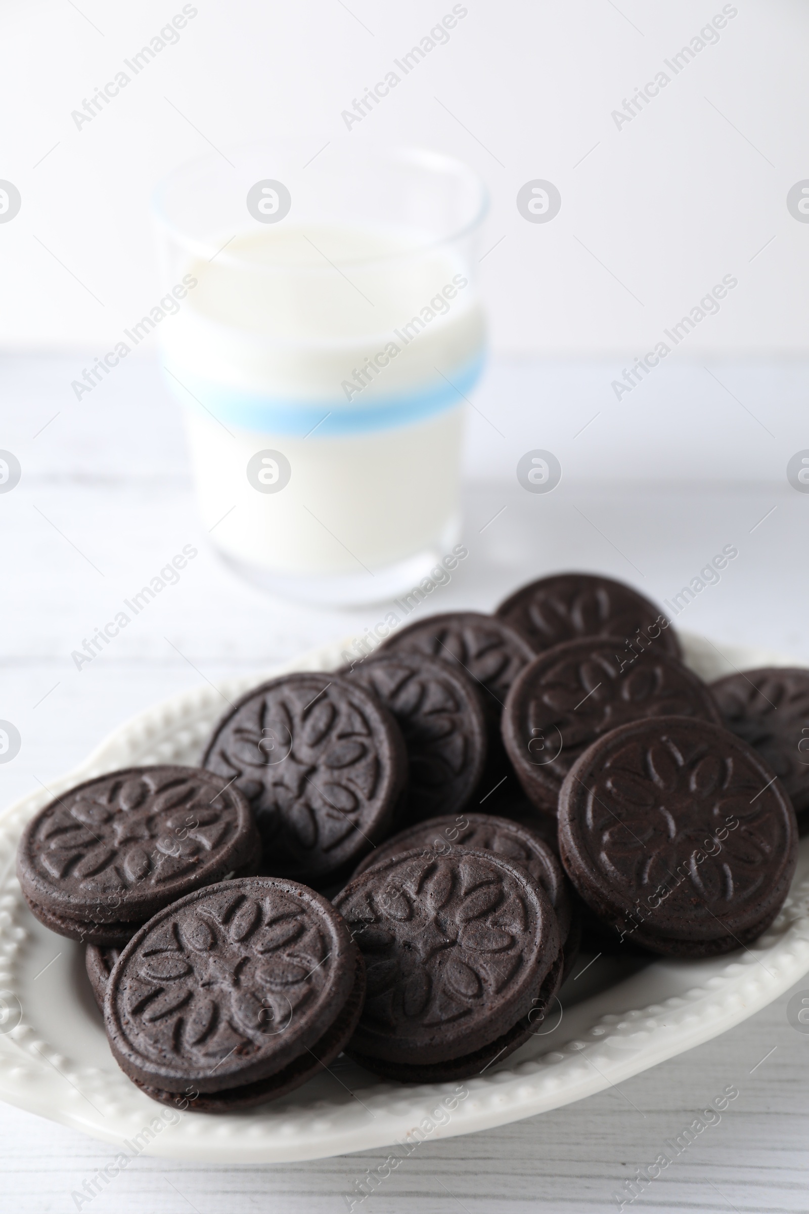 Photo of Tasty sandwich cookies and milk on white wooden table