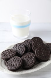 Photo of Tasty sandwich cookies and milk on white wooden table