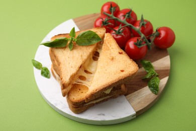 Photo of Pieces of toasted bread with melted cheese, tomatoes and basil on green background