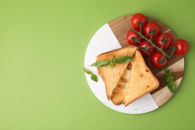 Photo of Pieces of toasted bread with melted cheese, tomatoes and basil on green background, top view. Space for text