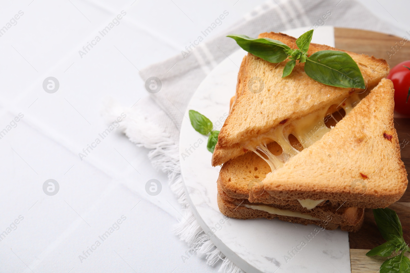 Photo of Pieces of toasted bread with melted cheese and basil on white table, space for text