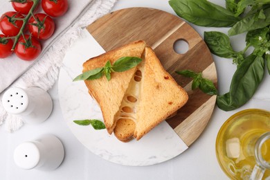 Photo of Pieces of toasted bread with melted cheese, tomatoes, oil and basil on white table, top view