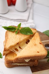 Photo of Pieces of toasted bread with melted cheese and basil on table