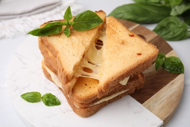 Photo of Pieces of toasted bread with melted cheese and basil on table, closeup