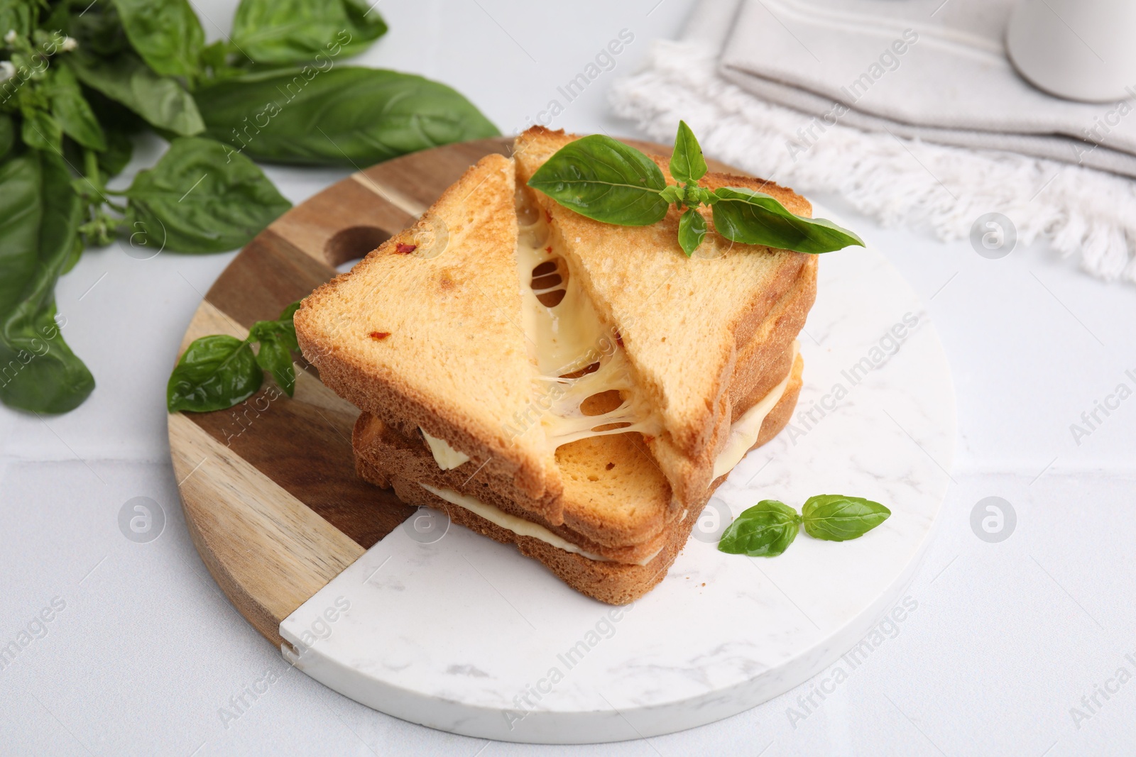 Photo of Pieces of toasted bread with melted cheese and basil on white table