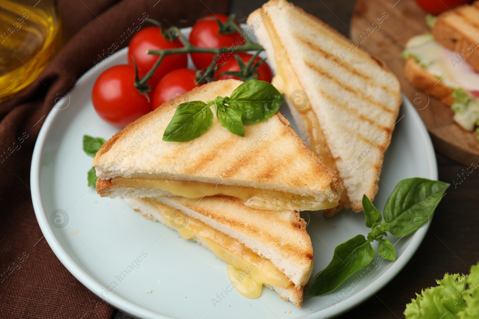 Photo of Pieces of toasted bread with melted cheese, tomatoes and basil on table