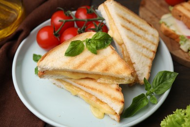 Photo of Pieces of toasted bread with melted cheese, tomatoes and basil on table