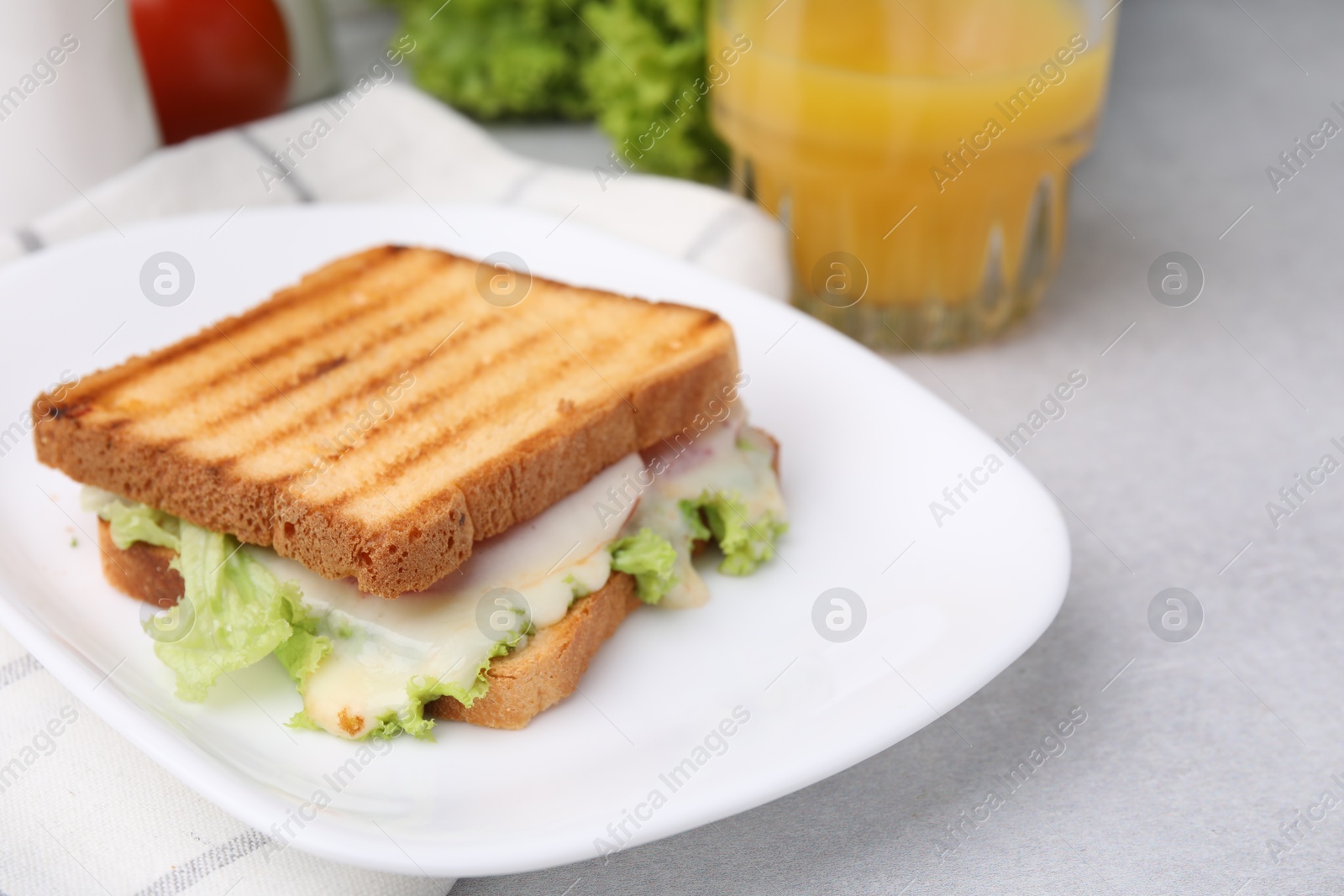 Photo of Tasty toasted bread with melted cheese and lettuce on light table