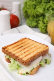 Photo of Tasty toasted bread with melted cheese and lettuce on table