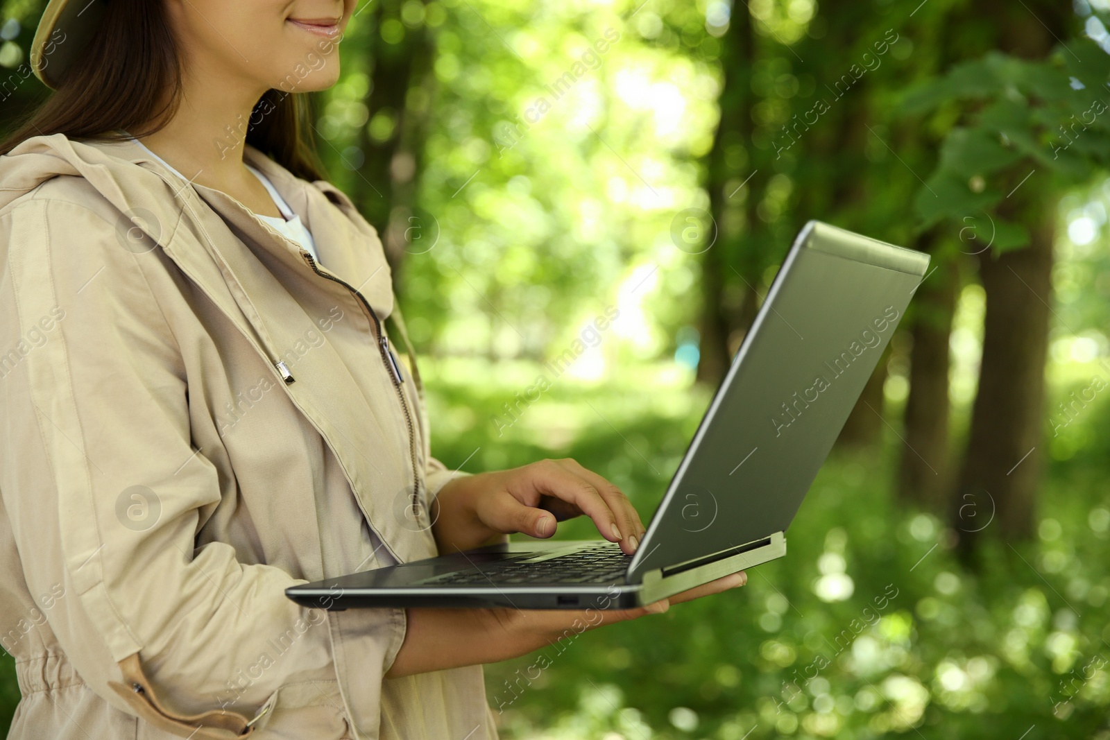 Photo of Forester with laptop examining plants in forest, closeup