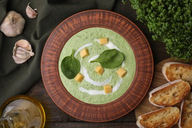 Photo of Delicious spinach cream soup with leaves and cheese in bowl on wooden table, flat lay