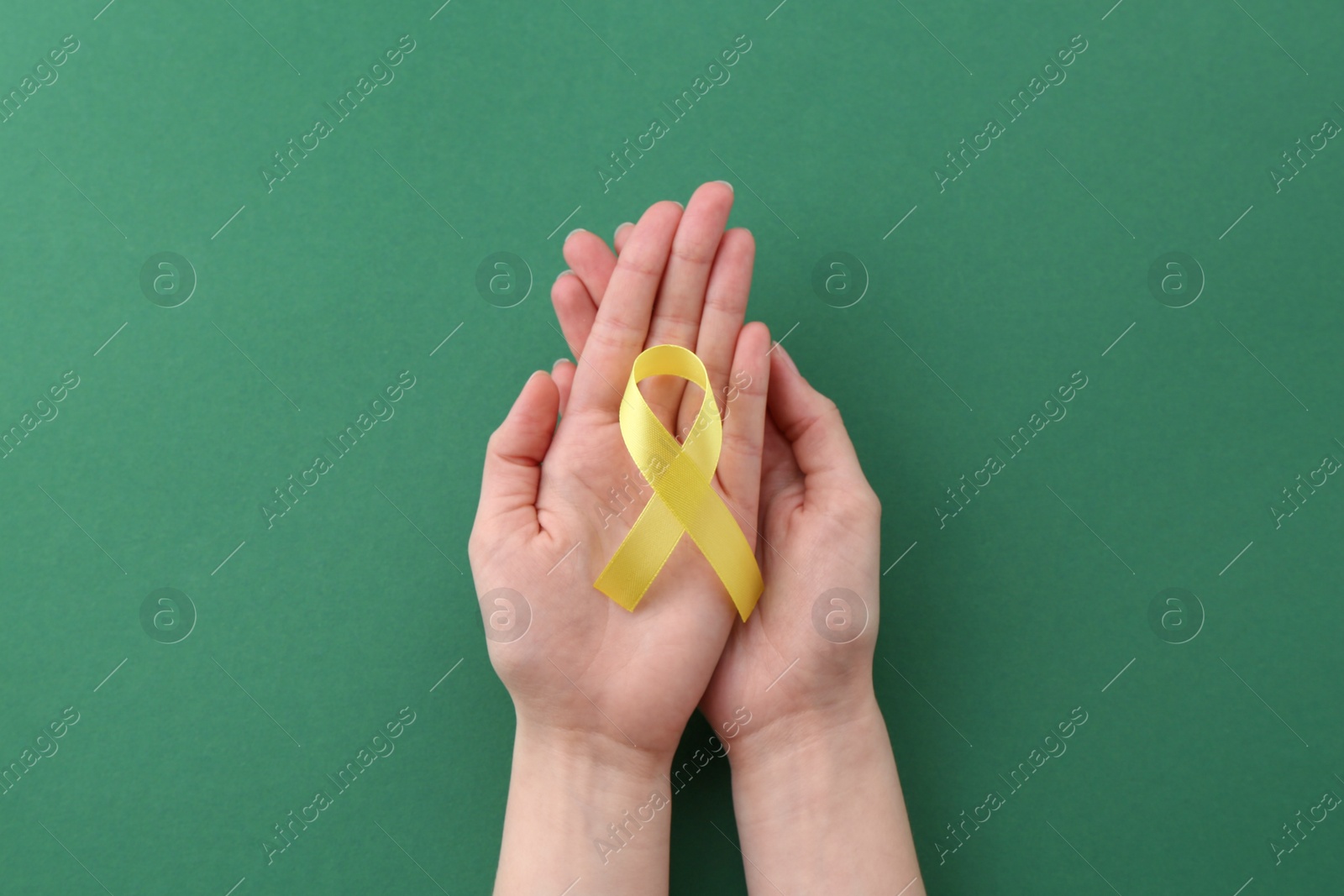 Photo of Woman with yellow awareness ribbon on green background, top view