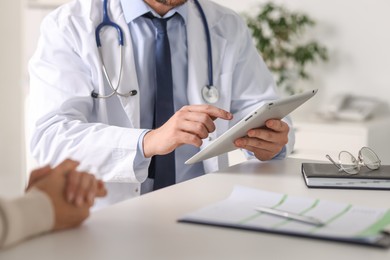 Professional doctor working with patient at white table in hospital, closeup