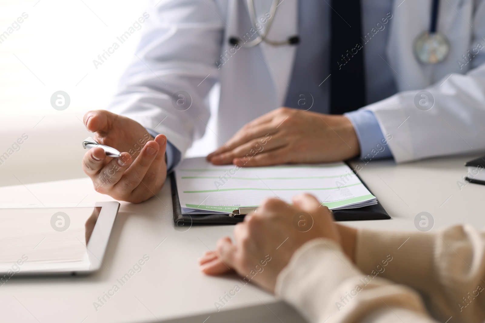 Photo of Professional doctor working with patient at white table in hospital, closeup