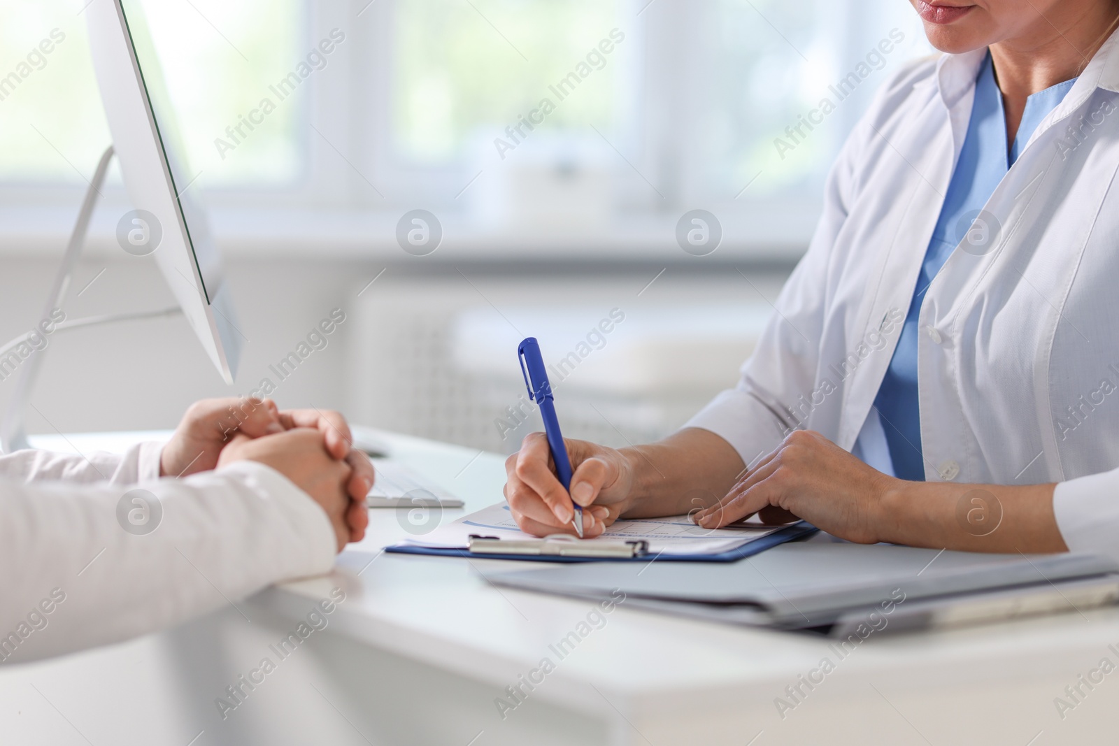 Photo of Professional doctor working with patient at white table in hospital, closeup