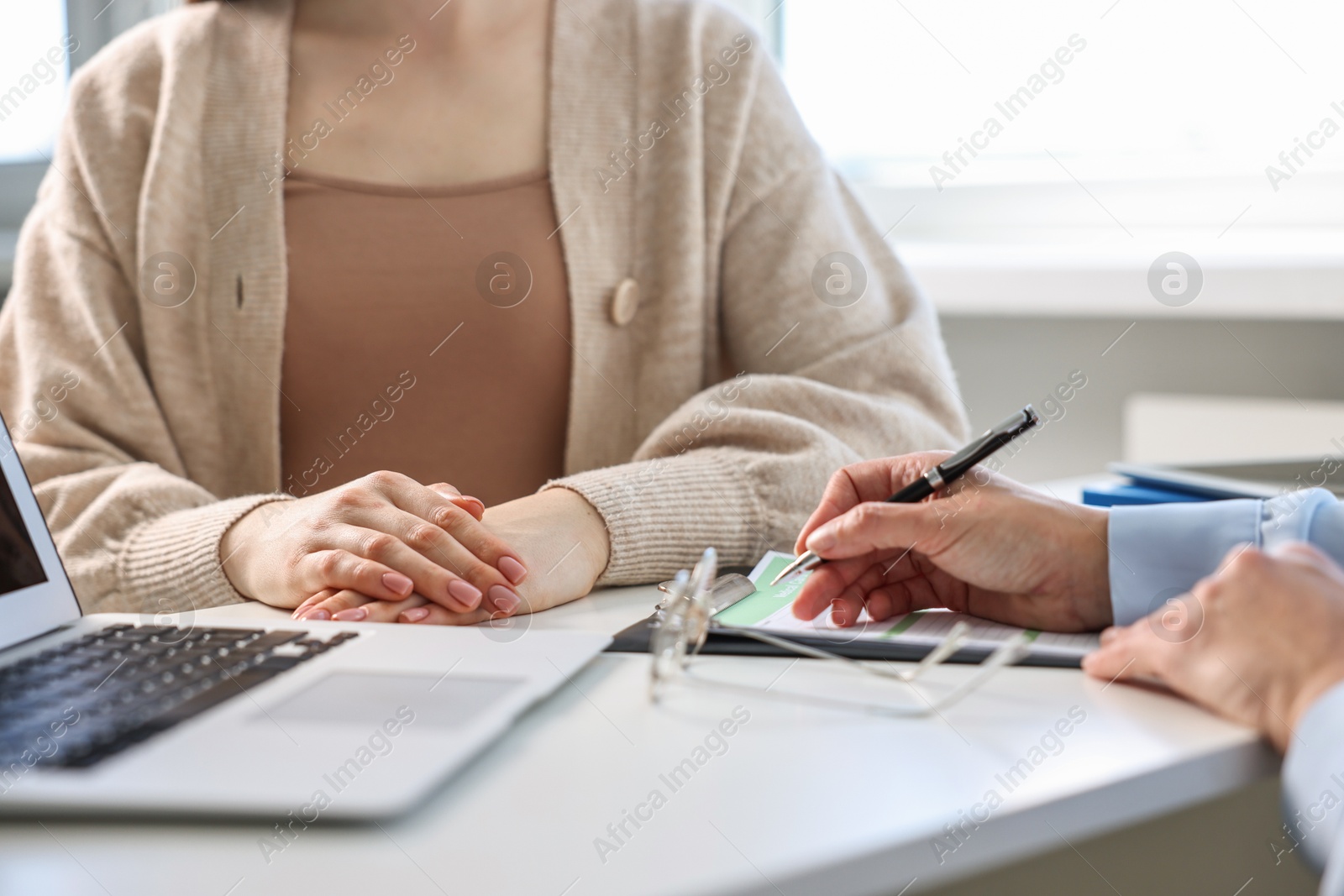 Photo of Professional doctor working with patient at white table in hospital, closeup