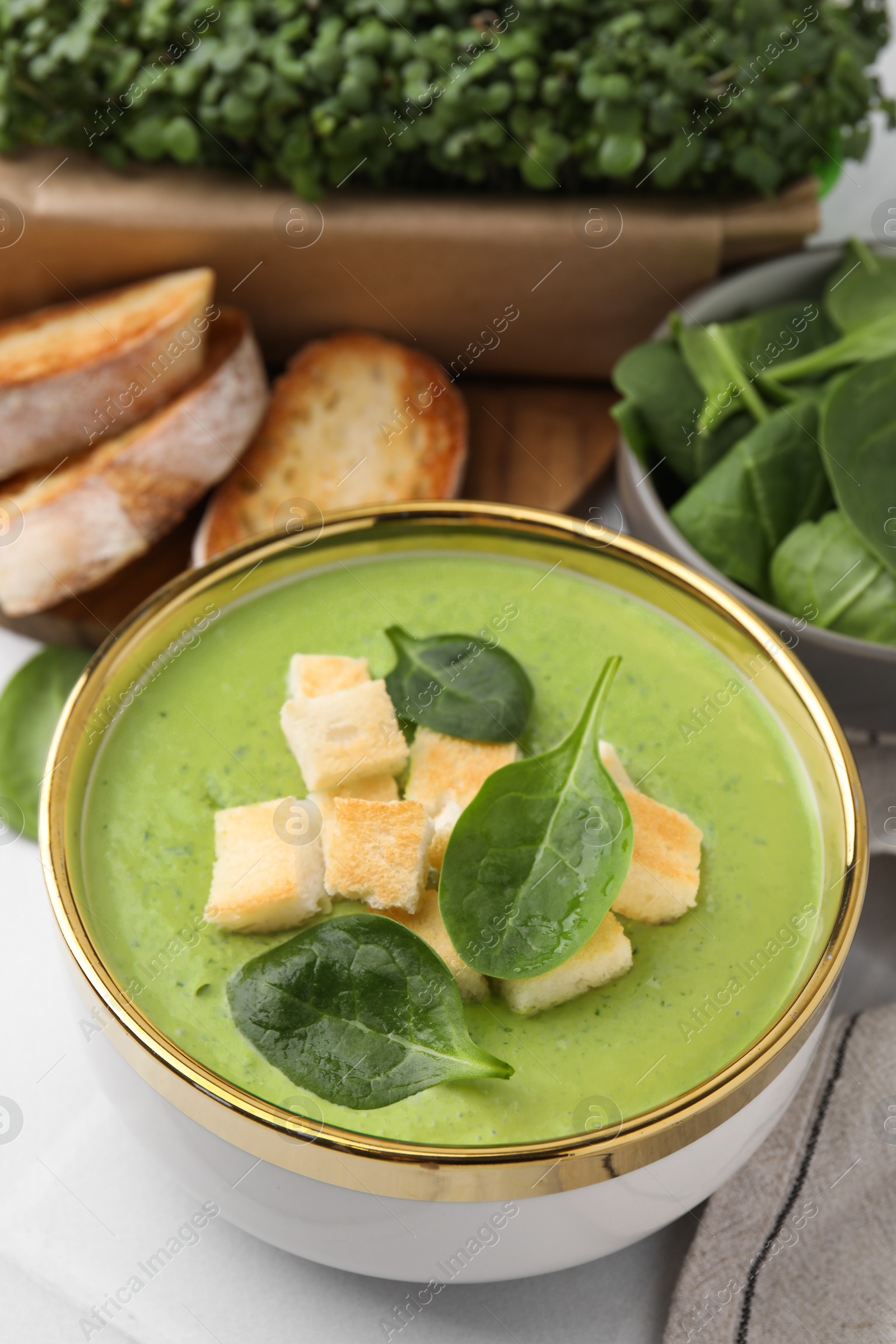 Photo of Delicious spinach cream soup with croutons in bowl on table